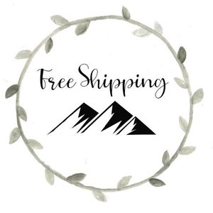 May include: A black and white illustration of two mountains with the text "Free Shipping" in a grey watercolour wreath.