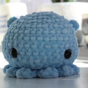 May include: A soft, blue crocheted octopus plush toy with black button eyes.