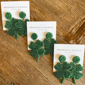 May include: Three pairs of green beaded shamrock earrings on white cards with the text "Brookhaven Baubles" on each card.