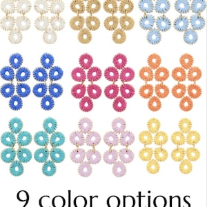 May include: Nine pairs of chandelier earrings in various colors, including white, tan, light blue, dark blue, pink, orange, teal, lavender, and yellow. Each earring features a woven design with a floral pattern. The text "9 color options" is at the bottom.