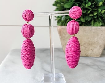 May include: Pink woven paper earrings with three round beads and a long oval bead.