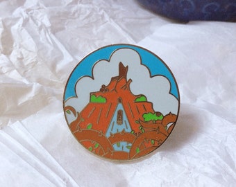 Può includere: Una spilla in smalto dorata che rappresenta una versione cartoon delle montagne russe Space Mountain a Walt Disney World. La spilla mostra la montagna con un cielo blu e nuvole bianche sullo sfondo.