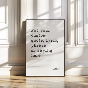 May include: A framed print with the text "Put your custom quote, lyric, phrase or saying here" in black font. The print is in a black frame and is displayed against a white wall.