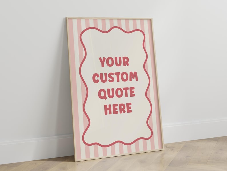 May include: A framed poster with a light wood frame. The poster features a cream-colored background with pink vertical stripes. A wavy-edged shape in the center contains the text "YOUR CUSTOM QUOTE HERE" in a dark pink color.