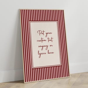 May include: A rectangular framed wall art piece featuring a vertical striped pattern in alternating shades of dark red and light pink. The centre contains a cream-coloured rectangular panel with the dark red text: Put your custom text. saying or lyrics here.