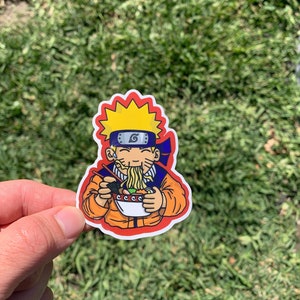 May include: A colorful sticker featuring an anime character with spiky yellow hair, a blue headband, and an orange jacket. The character is holding chopsticks and a bowl of ramen. The sticker has a red border and is set against a green background.