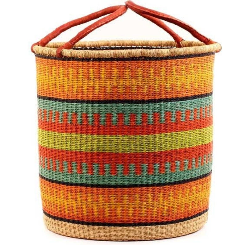 May include: A large, woven storage basket with a red, orange, green and brown striped pattern. The basket has two leather handles.
