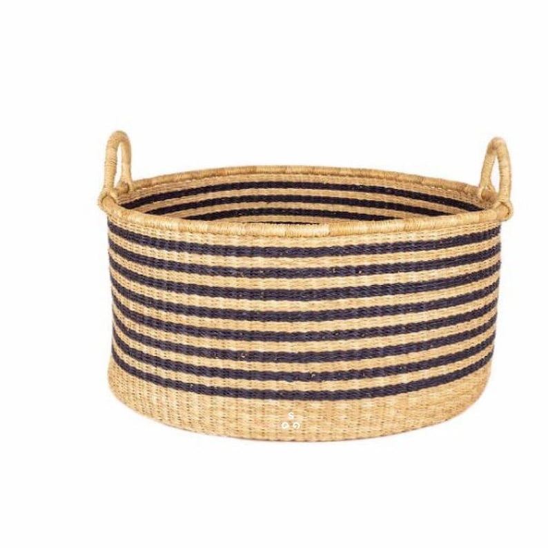 May include: A large, woven storage basket with black and natural colored stripes. The basket has two handles and is made of natural materials.
