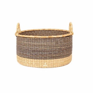 May include: A large, round, woven storage basket with black and natural colored stripes. The basket has two handles and a natural colored base.