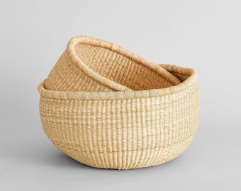 May include: Two woven baskets made of natural fibers, one nested inside the other. The baskets are round and have a light brown color.