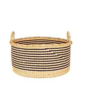May include: A large, round, woven storage basket with black and natural colored stripes. The basket has two handles on the sides.