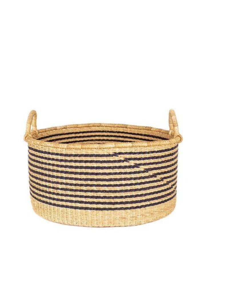 May include: A large, round, woven storage basket with black and natural colored stripes. The basket has two handles on the sides.