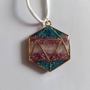May include: A gold-toned necklace with a hexagonal pendant filled with pink and blue glitter. The pendant is shaped like a geometric crystal.