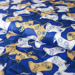 May include: Blue fabric with a repeating pattern of white and gold video game controllers.