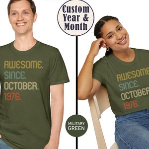 May include: A military green short-sleeved t-shirt featuring the text "AWESOME. SINCE. OCTOBER. 1976." printed in a stacked, multi-colored retro font. The shirt includes a circular graphic indicating "Custom Year & Month" and "MILITARY GREEN".