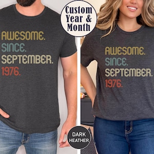 May include: A dark heather gray short-sleeve t-shirt featuring the text "AWESOME. SINCE. SEPTEMBER. 1976." printed in a retro-style font with gold, teal, and red colors. The shirt has a crew neckline and a standard fit, showcasing a vintage-inspired design.