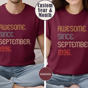 May include: A maroon short-sleeved t-shirt featuring the text AWESOME. SINCE. SEPTEMBER. 1996. in a retro-style font with orange, grey, and red colors. The shirt has a crew neckline and is displayed in a split-view format showing the front design.