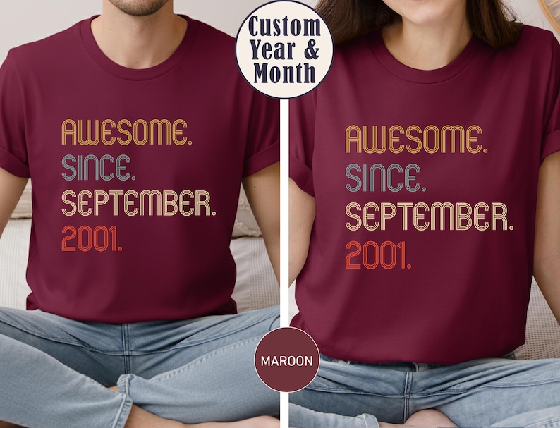 Op de afbeelding: Een bordeauxrood t-shirt met korte mouwen en de tekst "AWESOME. SINCE. SEPTEMBER. 2001." gedrukt in een meerkleurig lettertype in retrostijl. Het shirt heeft een ronde hals en een standaard pasvorm met een duidelijk grafisch ontwerp op de borst.