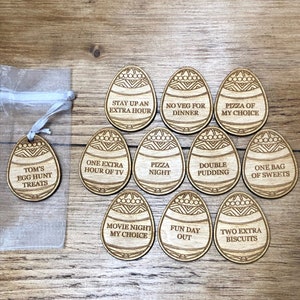 May include: Ten wooden Easter egg-shaped tokens with different fun activities written on them. The tokens are decorated with a geometric pattern. The activities include: "Stay up an extra hour", "No veg for dinner", "Pizza of my choice", "Tom's egg hunt treats", "One extra hour of TV", "Pizza night", "Double pudding", "One bag of sweets", "Movie night my choice", "Fun day out", and "Two extra biscuits".