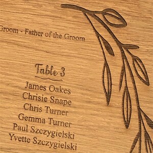 Puede incluir: Un cartel de asignaci&oacute;n de asientos de mesa de madera con un dise&ntilde;o floral. El cartel enumera los nombres de los invitados para las mesas 3 y 6. La mesa 3 incluye a James Oakes, Chrisie Snape, Chris Turner, Gemma Turner, Paul Szczygielski e Yvette Szczygielski.