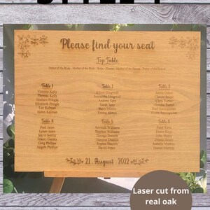 Puede incluir: Un plano de asientos de madera para una boda con el texto "Por favor, encuentre su asiento" y "Mesa principal" con los nombres de los miembros de la familia de la boda. El plano de asientos est&aacute; cortado con l&aacute;ser de chapa de roble real y tiene la fecha del 21 de agosto de 2022.