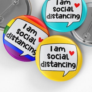 May include: Three round buttons with the text "I am social distancing" in a speech bubble. The buttons are blue, yellow, and rainbow.
