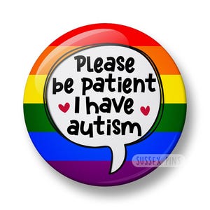 Pode incluir: Um botão redondo com um fundo gradiente de arco-íris e um balão de fala branco. O balão contém o texto "Please be patient I have autism" com dois corações vermelhos. O botão tem um acabamento brilhante.