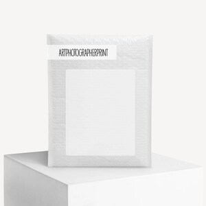 K&ouml;nnte beinhalten: Ein wei&szlig;er Luftpolsterumschlag mit einem rechteckigen Etikett mit der Aufschrift "ARTPHOTOGRAPHERPRINT". Der Umschlag steht auf einem wei&szlig;en W&uuml;rfel.