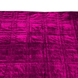 Może przedstawiać: Duży, pikowany koc w żywym kolorze magenta. Koc ma miękką, pluszową fakturę i idealnie nadaje się do dodania odrobiny koloru i ciepła do każdego pomieszczenia.