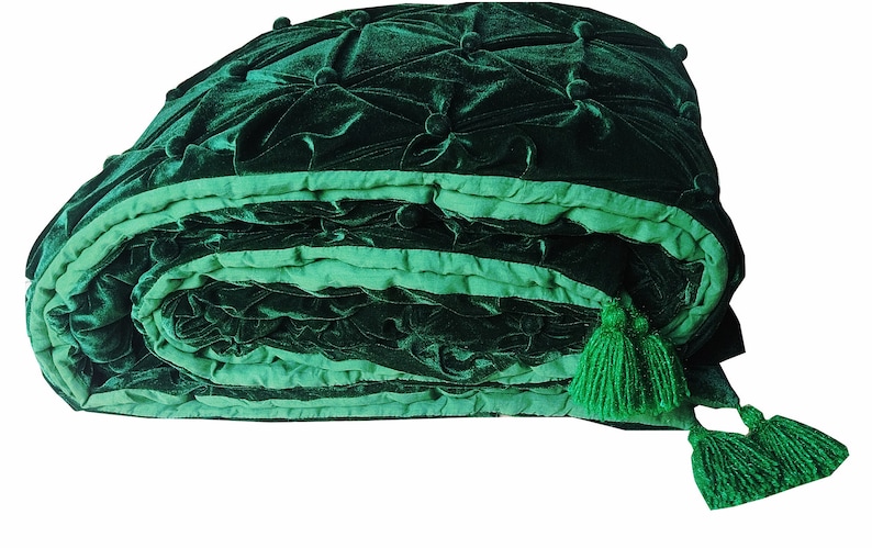 K&ouml;nnte beinhalten: Eine gr&uuml;ne Samtdecke mit gestepptem Muster und Quasten. Die Decke ist aufgerollt und hat ein hellgr&uuml;nes Futter.