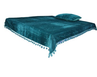 May include: Teal velvet bedspread with a pom-pom trim and a matching pillow.