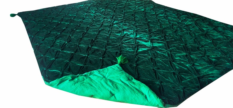 K&ouml;nnte beinhalten: Eine gr&uuml;ne, gesteppte Decke aus Samt mit gr&uuml;ner Satin-Futter und Quasten an den Ecken.