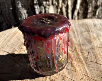 May include: A glass jar with a purple and red wax lid. The jar is filled with dried herbs and flowers. The wax is dripping down the sides of the jar.