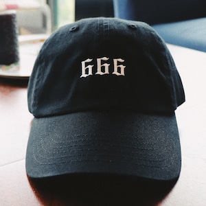 May include: A black baseball cap with a white embroidered "666" on the front.