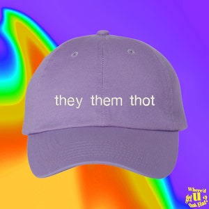 Puede incluir: Una gorra de béisbol morada con el texto "they them thot" bordado en blanco en la parte delantera.