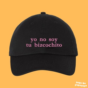 Könnte beinhalten: Schwarze Baseballkappe mit rosa gesticktem Text, der "yo no soy tu bizcochito" lautet.