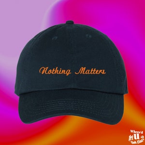 Peut inclure: Une casquette de baseball bleu marine avec le texte "Nothing Matters" brodé en orange sur le devant.