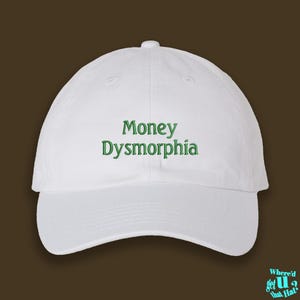 May include: White baseball cap with green embroidered text that reads "Money Dysmorphia".