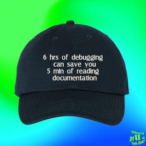May include: A dark navy blue baseball cap featuring white embroidered text that reads: 6 hrs of debugging can save you 5 min of reading documentation. The cap has a structured crown, a curved brim, and a button at the top centre of the fabric.