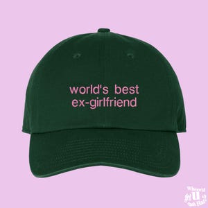 May include: A dark green baseball cap with the text "world's best ex-girlfriend" embroidered in pink.