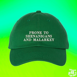 Puede incluir: Una gorra de béisbol verde con texto bordado en blanco que dice "Prone to Shenanigans and Malarkey".