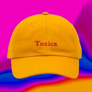 May include: A yellow baseball cap with the word "Toxica" embroidered in red on the front.