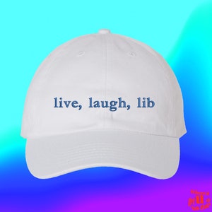 May include: White baseball cap with blue embroidered text that reads "live, laugh, lib".