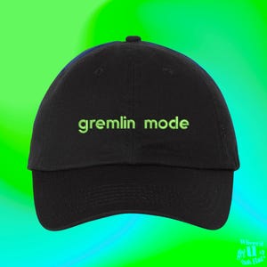 May include: Black baseball cap with the text "gremlin mode" embroidered in green.