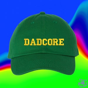 May include: A green baseball cap with the word "DADCORE" embroidered in gold on the front.