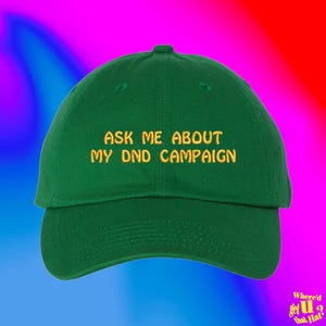 Puede incluir: Una gorra de béisbol verde con el texto "Ask me about my DND campaign" bordado en amarillo.