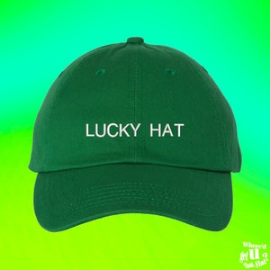 Puede incluir: Una gorra de béisbol verde con bordado blanco que dice "LUCKY HAT".