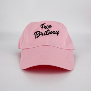 May include: A pink baseball cap with black embroidery that reads "Free Britney".