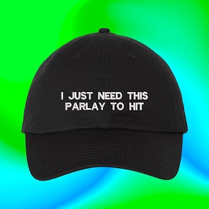 May include: Black baseball cap with white embroidered text that reads "I just need this parlay to hit".