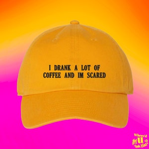 May include: A yellow baseball cap with black text that reads "I drank a lot of coffee and I'm scared".
